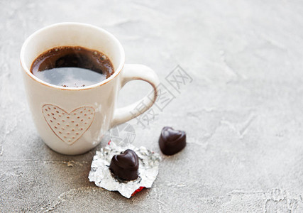 混凝土背景上的一杯咖啡和巧克力糖图片