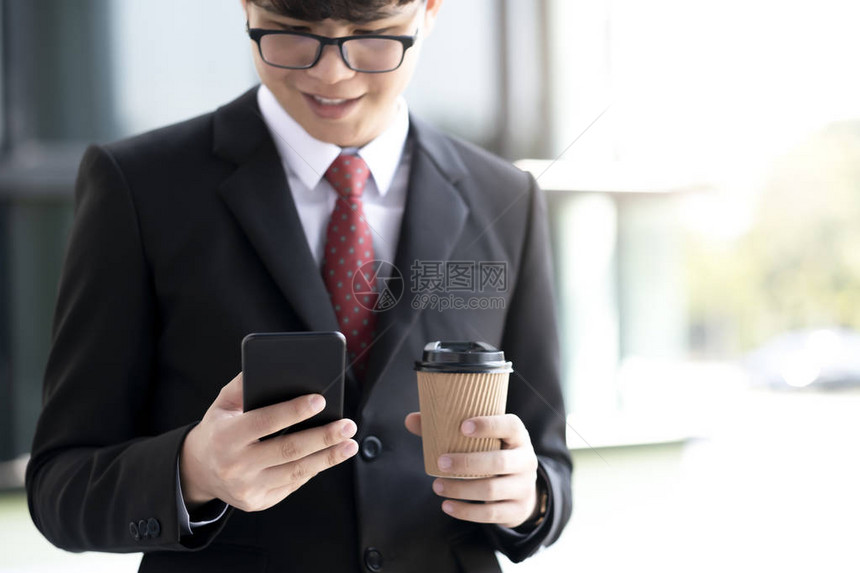 年轻的商人在办公室外使用手机应用程序发短信图片