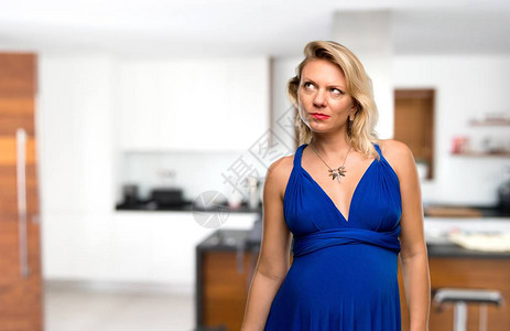 穿着蓝裙子的怀孕女金发孕妇有疑惑在家中图片