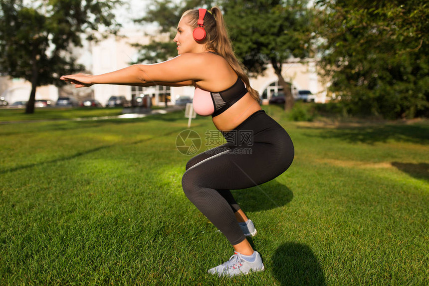 参加顶部的年轻有吸引力且体型较大的女子和在城市公园用草花时间进行体育锻炼图片