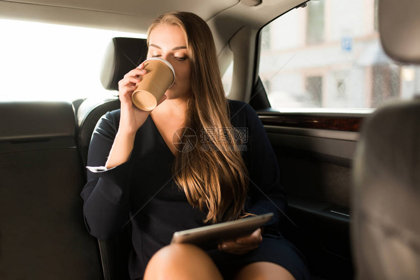 身着黑色衣服的年轻有吸引力商业女青年坐在汽车后座上图片