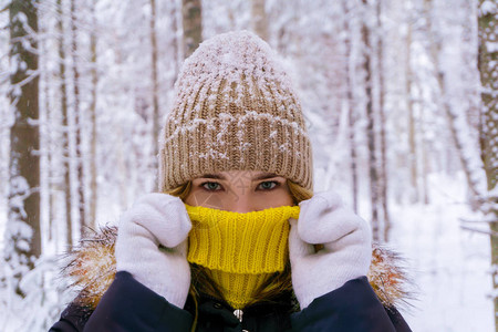 冬天森林中美丽的女孩将脸遮在毛衣领上图片