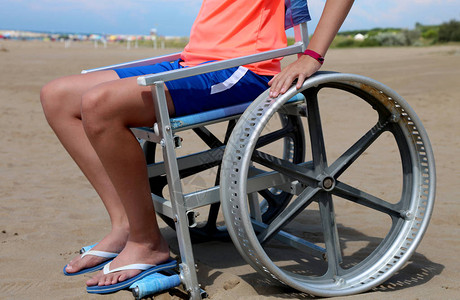 在海滩上坐在特殊轮椅上的残疾男孩图片