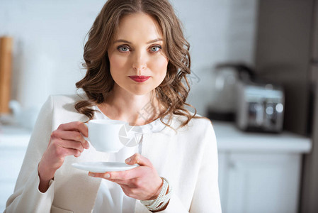 美丽的女人拿着咖啡杯在厨房吃早图片