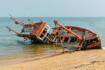 一艘破损的渔船靠岸倒在一边遭遇海难背景图片
