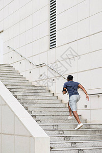背着智能手机的无法辨认的运动员在晨练时跑上混凝土图片
