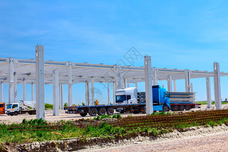 载有拖车的卡车正在将长重混凝土束运到工业大厦图片