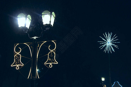 黑暗中明亮的新年的节日花环夜街上的圣诞灯饰以小铃铛的形式照图片