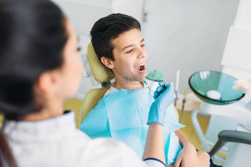 带牙印膏的女牙医坐在牙科椅上的男孩儿科牙图片