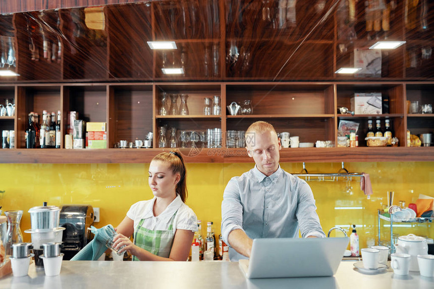 在咖啡店老板用笔记本电脑与咖啡店老板在柜台做酒吧招图片