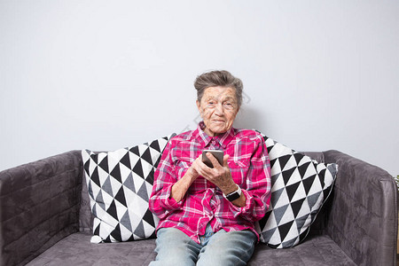 白发苍满脸皱纹的白人老妇坐在客厅的沙发上背景图片