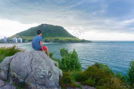 男孩坐在休闲岛的岩石上图片