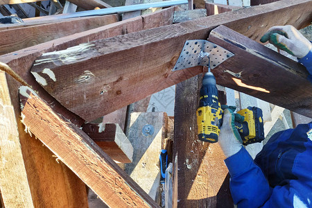 工人用螺丝起子2019年在屋顶的木筏上扭动图片