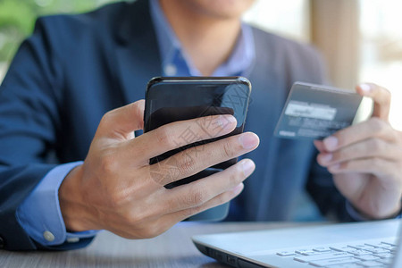 商人持有信用卡并使用智能手机进行网上购物图片