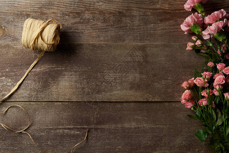 木制背景上美丽嫩粉色花朵和丝带的顶视图图片
