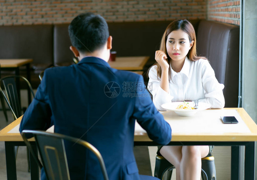 无聊的亚洲女孩坐在咖啡厅和男友一起吃午饭图片