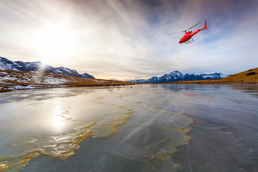 在结冰的湖面上飞行的红色直升机图片