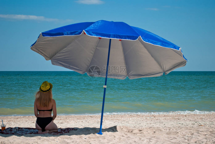 一个漂亮的女孩坐在沙滩伞下图片