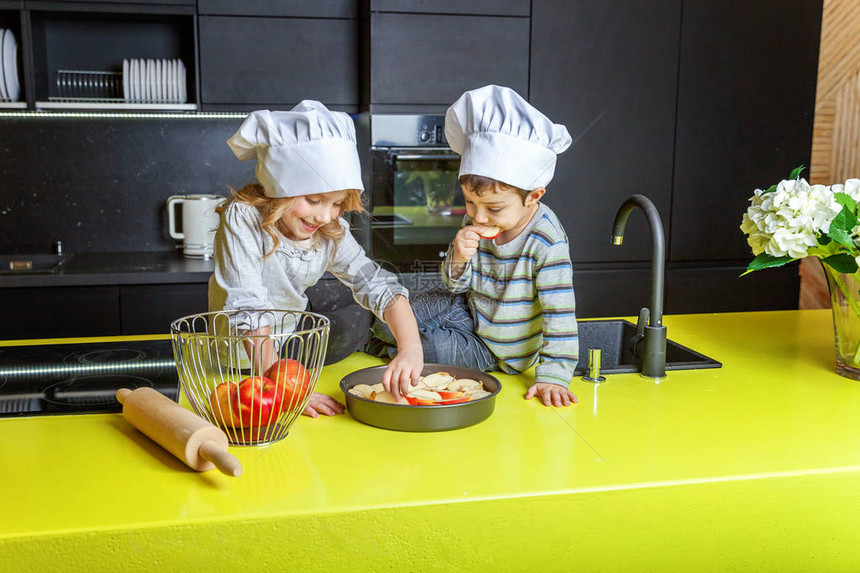 带厨师帽的小女孩和男孩在厨房准备烤自制苹果派图片