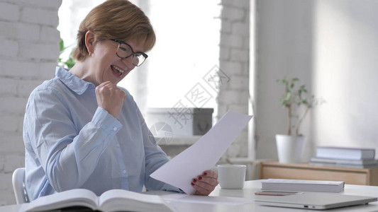 工作场所成功的老年妇女阅读文件令图片
