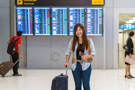 亚洲旅客带着护照带着行李走过飞行板图片