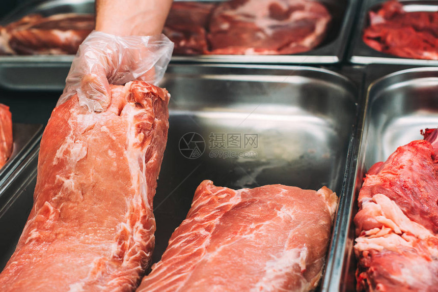 肉店屠夫的手拿着肉块在店里在超市展示的新鲜肉类的最佳报价肉店里的生牛肉和猪肉各种生肉新鲜图片