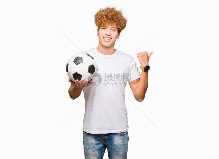 英俊的年轻帅哥拿着足球指尖手举大拇指向一边图片