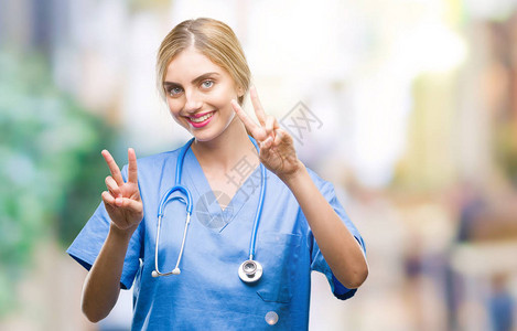 年轻漂亮的金发外科医生护士女人在孤立的背景下微笑着看镜头图片