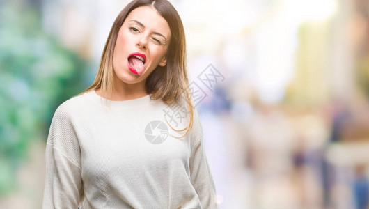年轻美女随身带着白毛衣与孤立的背景相伴用有趣的表情来表达快乐的舌图片