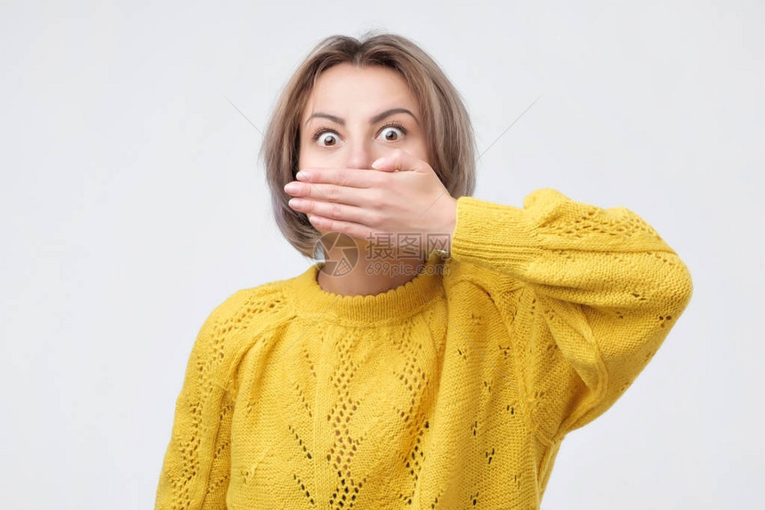 令人吃惊的消息穿着黄色毛衣的女士惊讶地用手把嘴盖上图片