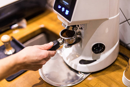 来自咖啡机研磨机的咖啡架中的新鲜咖啡粉图片