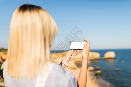 身着太阳眼镜的金发年轻女子拿着带白色屏幕的电话图片
