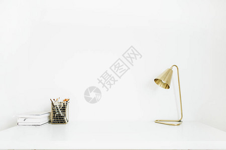 白色桌面上的金灯和文具最起码的图片