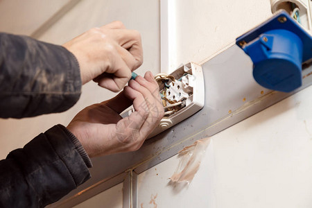 修理电源插座墙上插座的男电工手的特写危险概念高压风图片