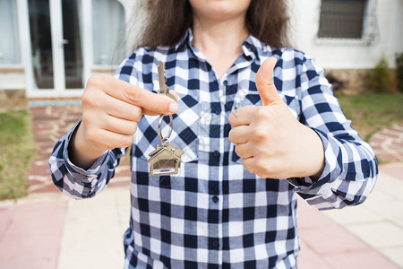 手持钥匙和锁链在房子的形状上新家背景上的房屋钥匙图片