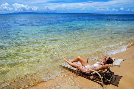 身穿比基尼的年轻妇女躺在斐济Taveuni岛的椅上背景图片