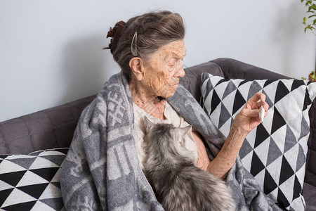一位白发苍皱纹深邃的高加索老奶正坐在家里的沙发上高清图片