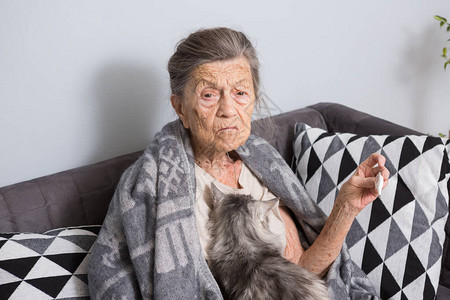一位白发苍皱纹深邃的高加索老奶正坐在家里的沙发上高清图片