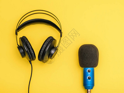 黄色背景上的黑色耳机和蓝色麦克风用于录音交流和图片