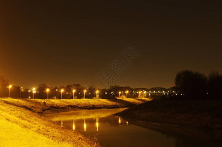 乡村夜景水道沿河岸点亮的黄色的暖光落在水面上夜景图片