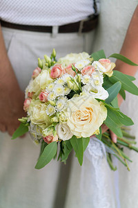 新娘举着粉红和蜜蜂的婚礼花束新鲜花和叶图片
