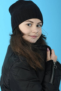 身穿冬季黑色外套和帽子蓝色背景的肖图片