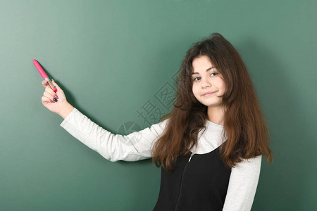 绿色背景的微笑的小女学生年轻俏皮的女孩手里图片