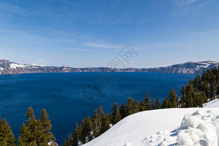 在克拉泽湖的深蓝水与山岸上的白雪形成对比图片