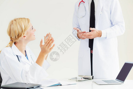 医院办公室的年轻女医生与站在桌子旁边的另一位男医生交谈医疗保健专图片