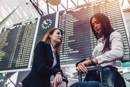 两名女游客站在国际机场飞行信息展露处附近图片