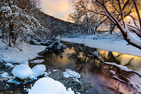 俄罗斯冬季日落时在森林中流动的河流景观图片