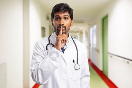印度男医生或医护人员在嘴唇上举起食指图片