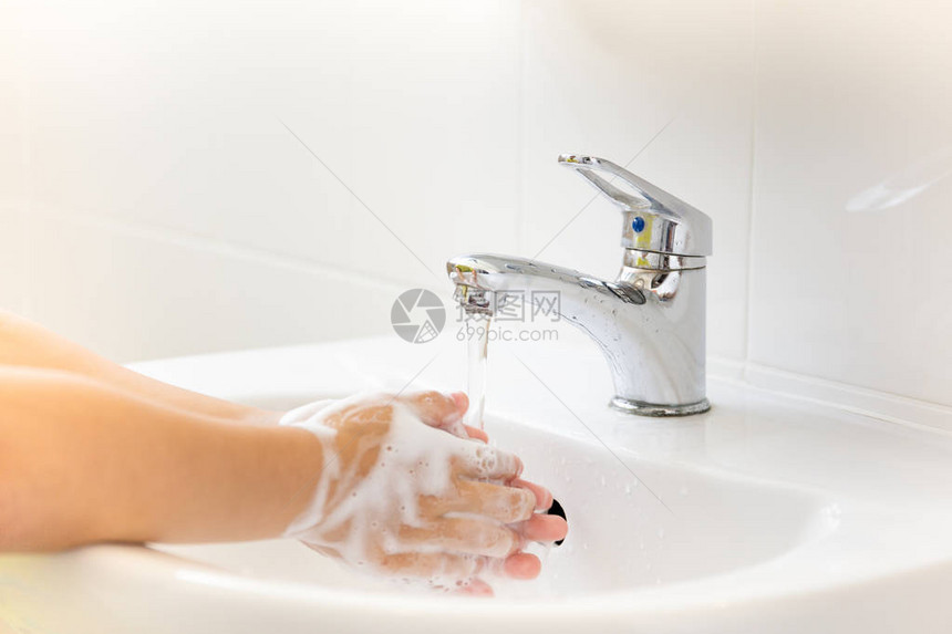 自来水儿童在浴室水龙头下用肥皂洗手图片