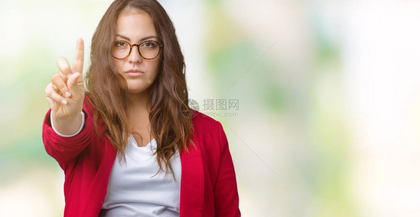 身穿优雅夹克和眼镜的漂亮大码年轻女商人在孤立的背景下指着手图片